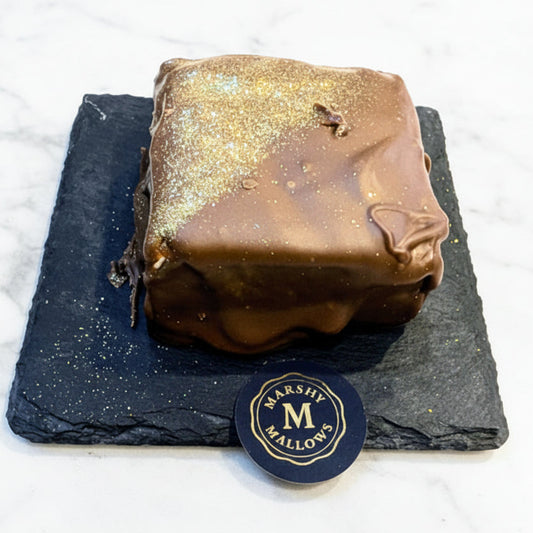 Chocolate-covered treat on a slate surface with a Marsh Mallows logo.